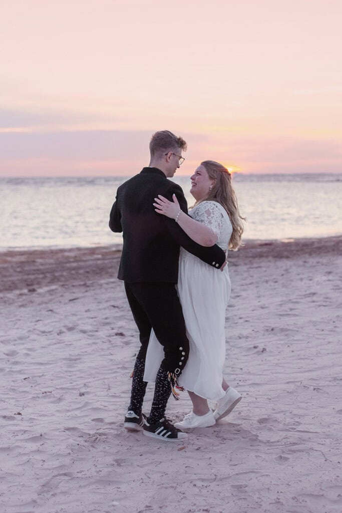 Bryllupsfotografering av par på stranden under solnedgang, romantisk og stemningsfullt.