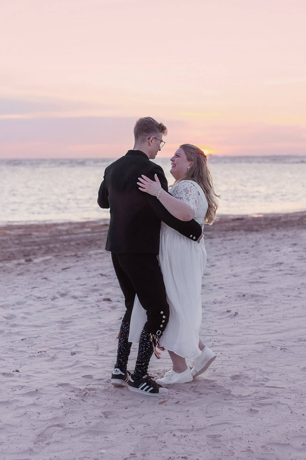 Bryllupsfotografering av par på stranden under solnedgang, romantisk og stemningsfullt.