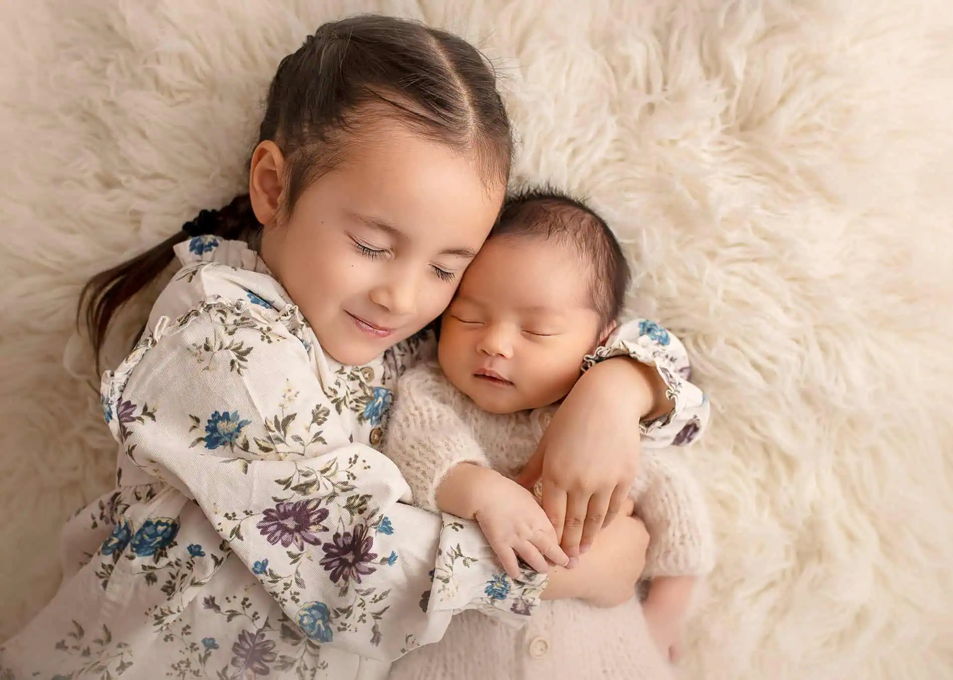 To søsken koser seg på myk, lys pelsdekket overflate.