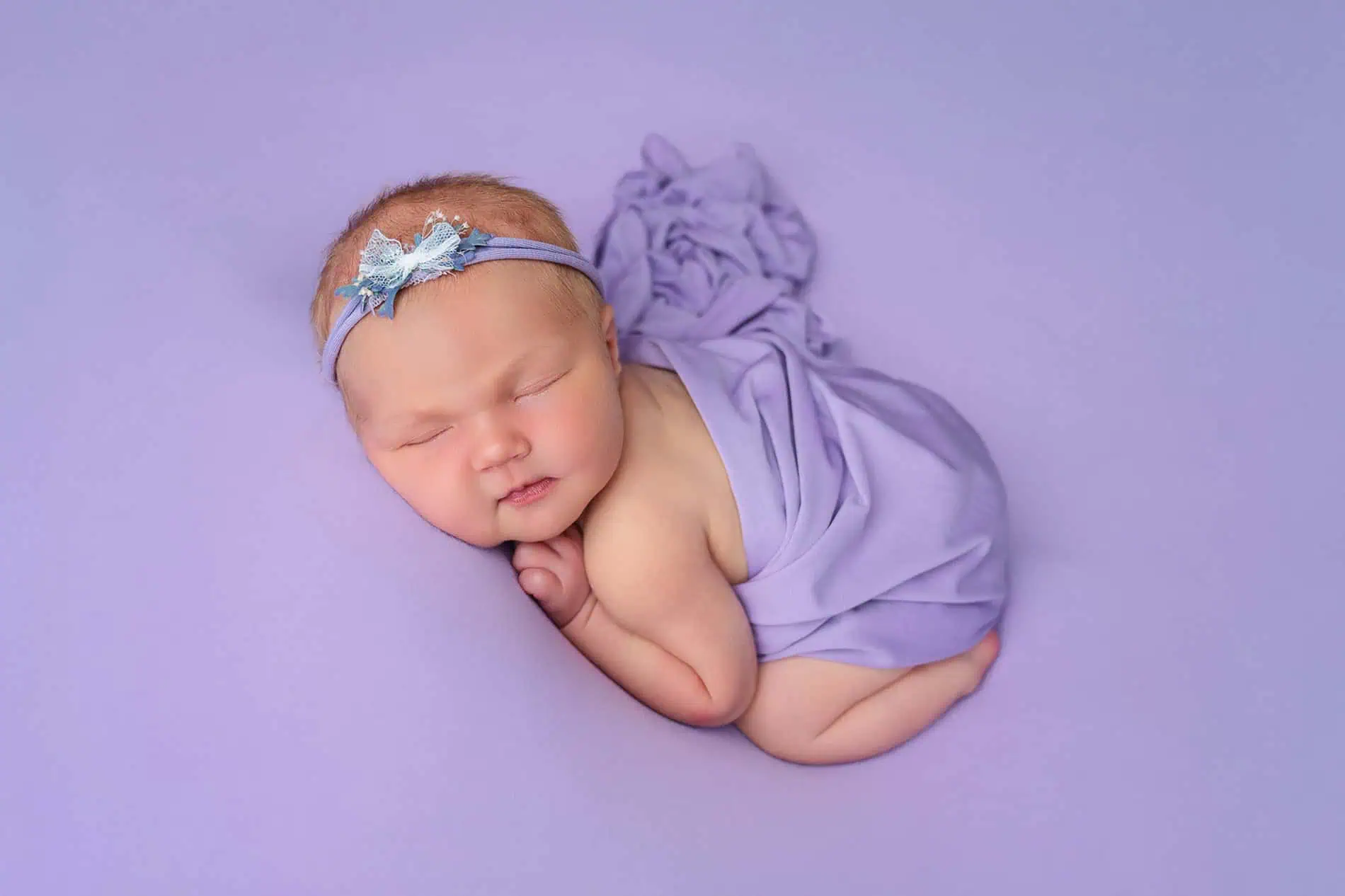 Nyfødtbaby sovende med blomsterhodebånd, portrettfoto i Oslo.