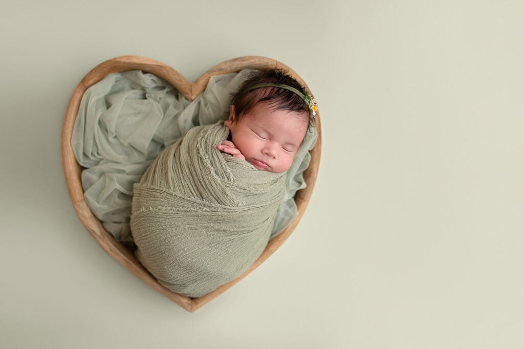 Nyfødt baby sovende i hjerteformet kurv, fotografi i Oslo.