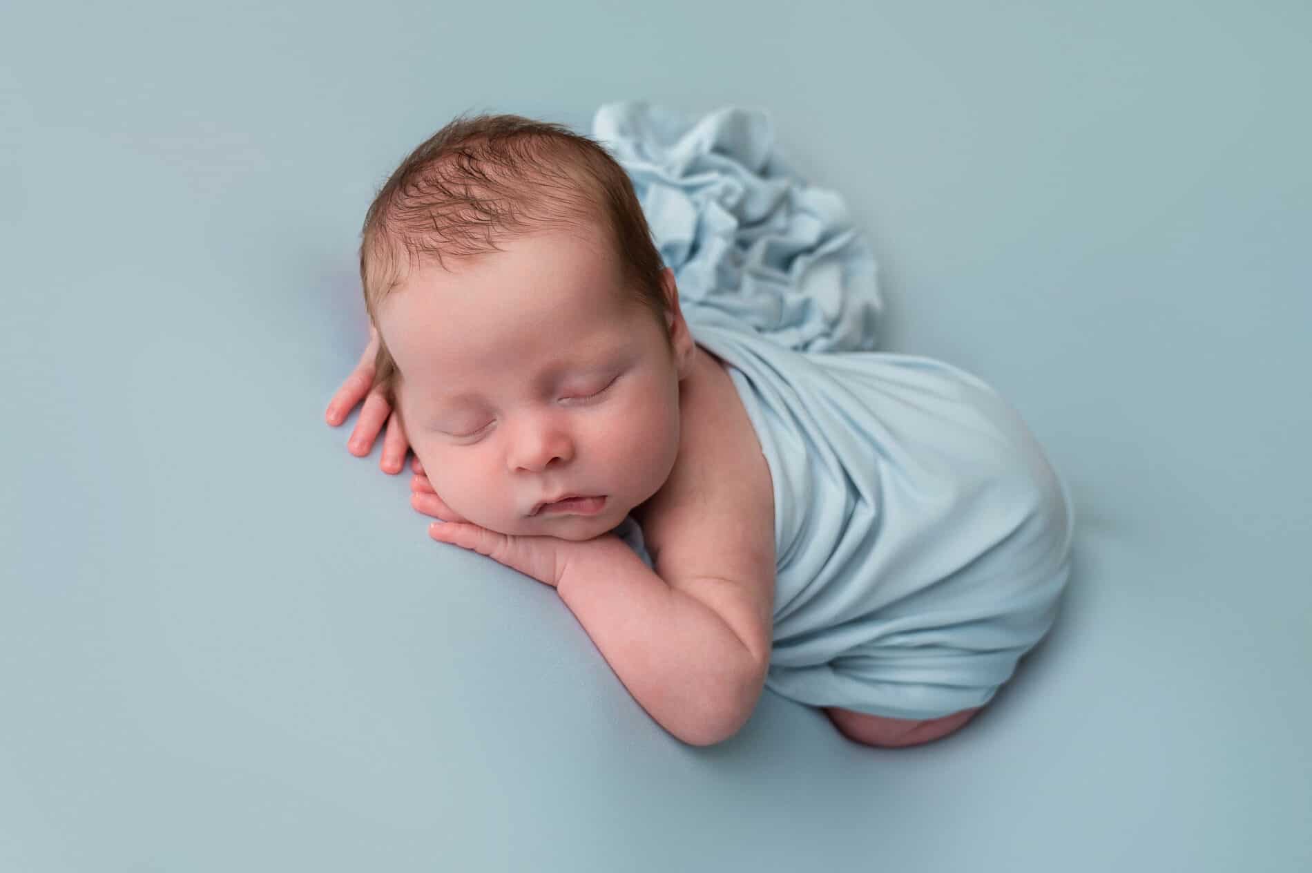 Soveende nyfødt baby fotografert under nyfødtfotografering, rolig og søvnig.